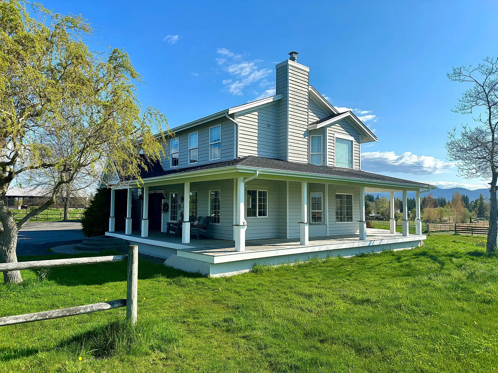 White farmhouse with wraparound porch freshly painted by Hilltop Painting in Whatcom County, WA